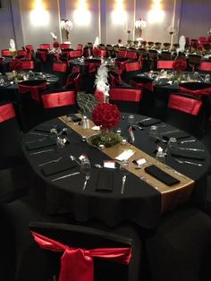 the tables are set up with black linens and red sashes, silverware