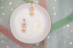 two daisies on a white plate with the number six hanging from it's side