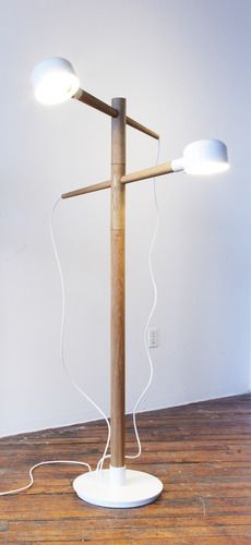 a wooden floor lamp with two white lamps on it