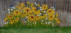 a painting on the side of a fence with yellow and white flowers