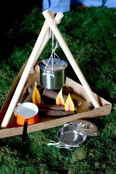 a small campfire is set up in the grass with some cooking utensils