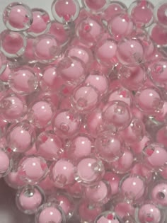 some pink beads are sitting on a white surface and there is no image in the top right corner