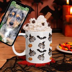 a cell phone is next to a cup with whipped cream and pumpkins on it