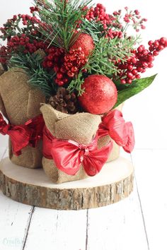 a christmas arrangement in burlap bags with red bows and pine cones on top