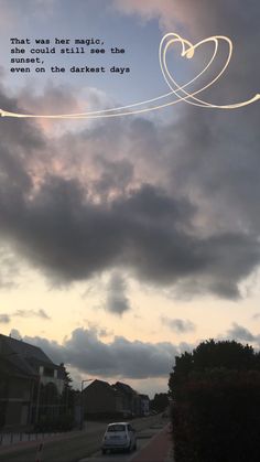 a car driving down a street under a cloudy sky with a quote written on it