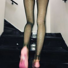 a woman in fishnet stockings and high heels walking up stairs with her pink shoe