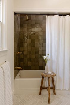 a white bath tub sitting next to a wooden stool