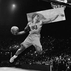 a basketball player jumping up into the air to dunk a ball in front of an audience