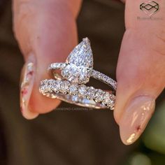 a close up of a person's hand holding two wedding bands and an engagement ring