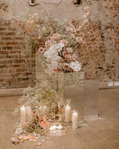 a tall vase filled with lots of flowers next to candles and other decorations on top of a floor