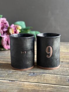 two black vases sitting on top of a wooden table