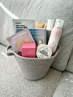 a basket filled with personal care items on top of a couch next to a pillow