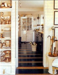 an open door leading to a kitchen with lots of dishes on the shelves and cupboards