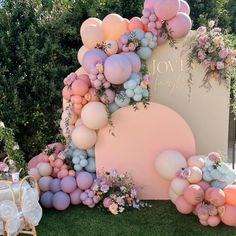 an outdoor event with balloons and flowers on the wall, in front of a sign that says joy