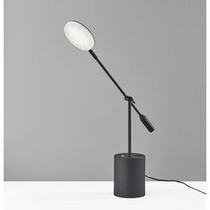 a lamp that is sitting on top of a table in front of a gray wall