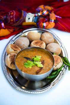 a silver plate topped with food next to a red cloth