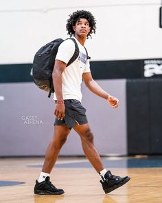 a man with a backpack walking on a basketball court