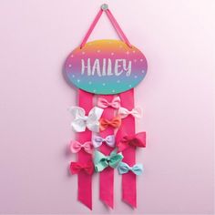 a pink and blue sign with bows hanging from it's side on a wall