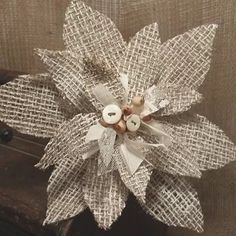 a close up of a flower made out of burlock and buttons on a piece of cloth