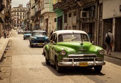 an old green car is parked on the street