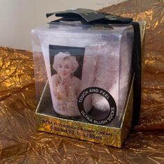 a box with a candle inside of it on a gold foiled tablecloth background