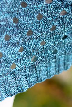 a blue knitted shawl with holes on it