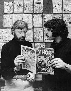 two men are looking at comics together