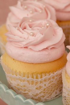 two cupcakes with pink frosting and lace on the top are sitting on a plate