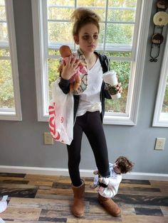 a woman holding a baby doll while standing next to a window