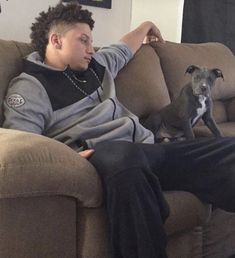 a man sitting on top of a couch next to a dog