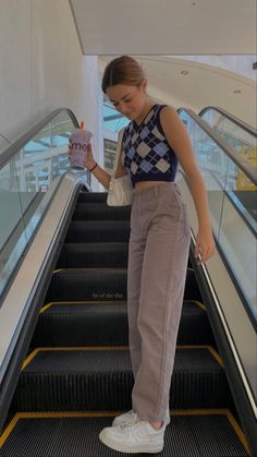 a woman is standing on an escalator and looking at her cell phone