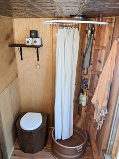 a toilet and shower in a small room with wood paneling on the walls,