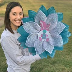 a woman holding a large blue and pink flower