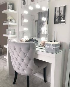 a white vanity with lights on it and a chair