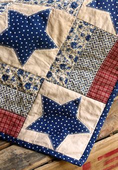 an old quilt is laying on top of a wooden table with blue and white stars