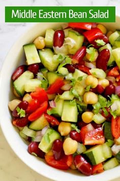 a white bowl filled with cucumber, beans and tomatoes