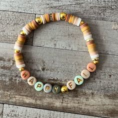 a beaded bracelet with the word happy written in small letters on it, sitting on top of a wooden floor