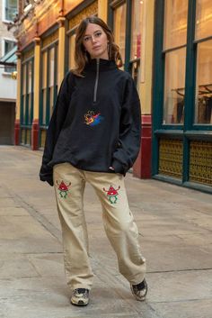 a woman standing on a sidewalk in front of a building Casual Fleece Half-zip Sweats, Casual Half-zip Fleece Sweats, Relaxed Fit Fleece Sweatshirt With Pockets, Winter Loungewear Sweats With Embroidered Logo, Long Sleeve Fleece Sweats With Embroidered Logo, Embroidered Sweatshirt For Streetwear In Winter, Embroidered Sweatshirt For Winter Streetwear, Casual Winter Sweats With Embroidered Logo, Casual Fleece Sweats With Embroidered Logo