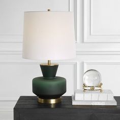 a green lamp sitting on top of a black table next to a white marble block