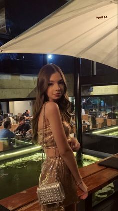 a woman standing in front of a table holding a white purse and looking at the camera