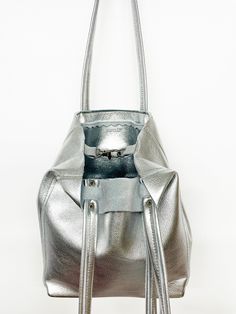 DESCRIPTION:Genuine leather tote bag, great for your essentials when you want a compact bag. Use around town for the weekend or an everyday bag. Perfect for travel as the bottom folds to pack flat.• Genuine leather with a metallic silver finish • Zipper closure OR Swivel lobster clasp and D-ring for closure• Interior pocket• Double leather strap with rivet detail• Reinforced leather bottom • Unlined with raw edges• Fringe detail on strap• Hand made• Made in USADIMENSIONS:9.5”H x 8”W x 4.5”D9.5" Bag Packs, Travel Free, Compact Bag, Genuine Leather Totes, Side To Side, Silver Zipper, Leather Cleaning, Zipper Top, Everyday Bag