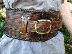 a man wearing a leather belt with metal buckles on his waist and the belt is made out of brown leather