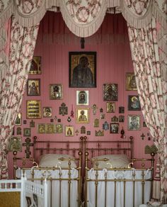 two beds in a room with pink walls and pictures on the wall