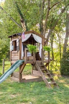 a tree house with a slide in the grass