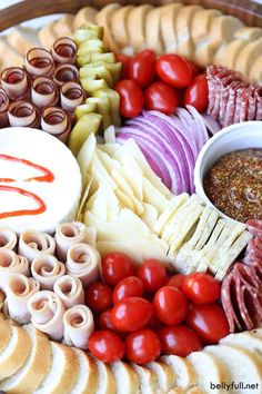 a platter filled with meat, cheeses and other food items including breadsticks