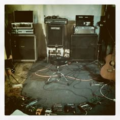 a room with guitars, amps and other musical equipment on the floor in it