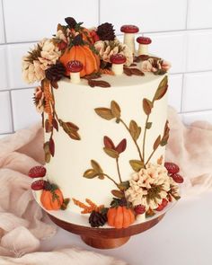 a white cake decorated with flowers and pumpkins