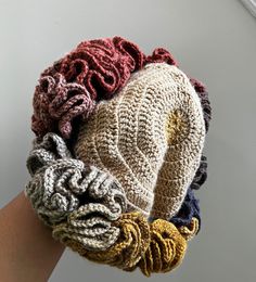 a woman's hand is holding several knitted items in her left arm,