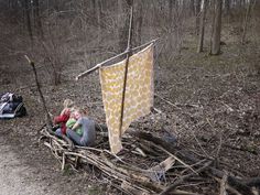 a small child sitting on top of a pile of sticks next to a yellow flag