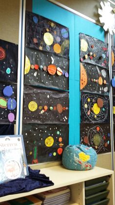 the space themed bulletin board is displayed in front of a bookshelf filled with children's artwork